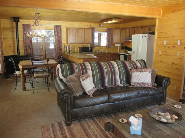 living room featuring a wood stove, beam ceiling, and wood walls