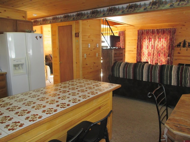 kitchen featuring carpet floors, white refrigerator with ice dispenser, wooden ceiling, and wood walls