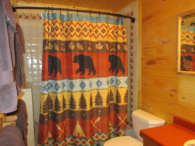 full bathroom featuring toilet, vanity, wooden walls, and shower / bath combo