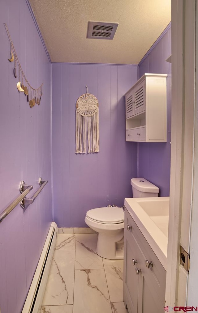 bathroom featuring vanity, a baseboard heating unit, toilet, and a textured ceiling