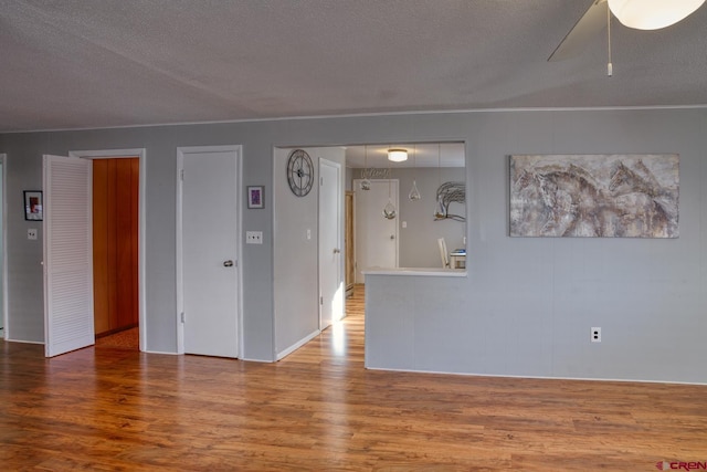 empty room with ceiling fan, wood-type flooring, and a textured ceiling