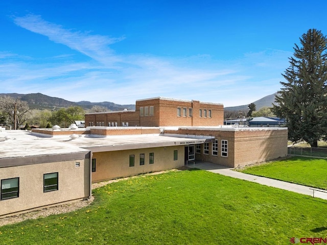 back of property with a mountain view and a lawn