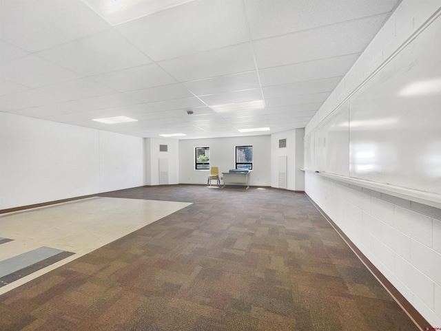 basement featuring a drop ceiling and dark colored carpet