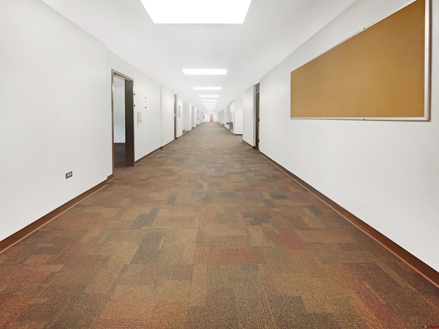 corridor featuring a skylight and dark carpet