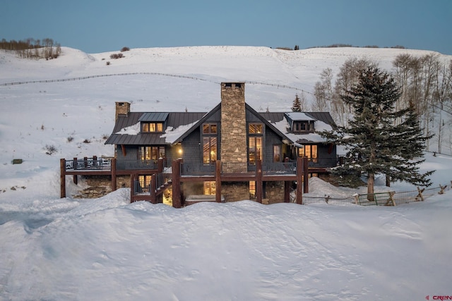 snow covered rear of property with a wooden deck