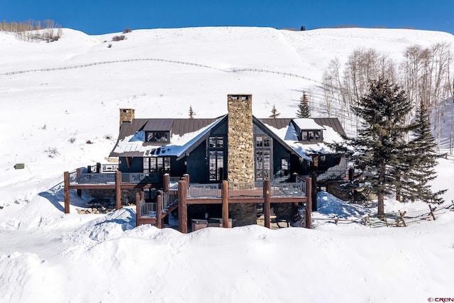 snow covered house featuring a deck with mountain view