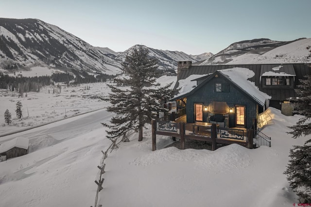 snow covered rear of property featuring a mountain view