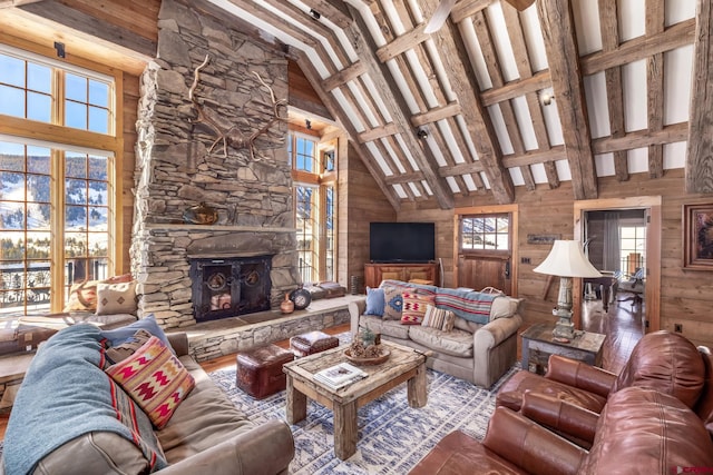 living room with beam ceiling, high vaulted ceiling, a stone fireplace, and wooden walls