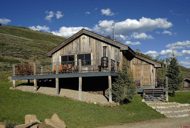 rear view of property featuring a wooden deck and a yard