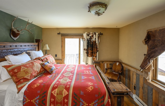 1294 County Road 734, Crested Butte, CO 81224 - bedroom featuring baseboard heating, a wainscoted wall, access to exterior, and wood finished floors