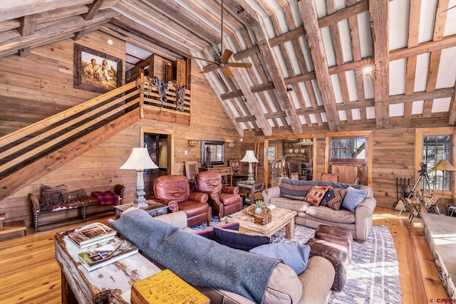 living room featuring ceiling fan, wood-type flooring, high vaulted ceiling, and wood walls