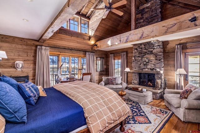 bedroom featuring wooden walls, high vaulted ceiling, beamed ceiling, a fireplace, and hardwood / wood-style flooring