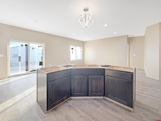 kitchen with hanging light fixtures, a center island with sink, and light wood-type flooring