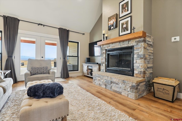 living room featuring french doors, high vaulted ceiling, a fireplace, and light hardwood / wood-style floors