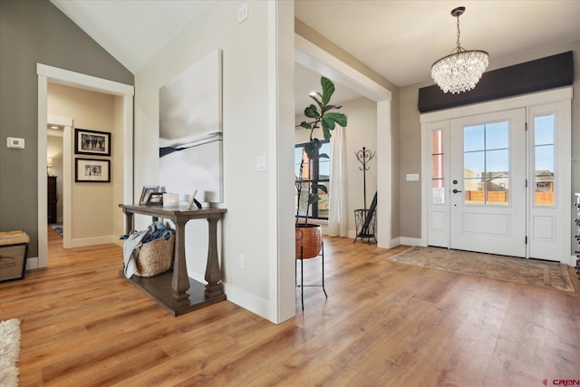 entrance foyer featuring vaulted ceiling, an inviting chandelier, and light hardwood / wood-style floors