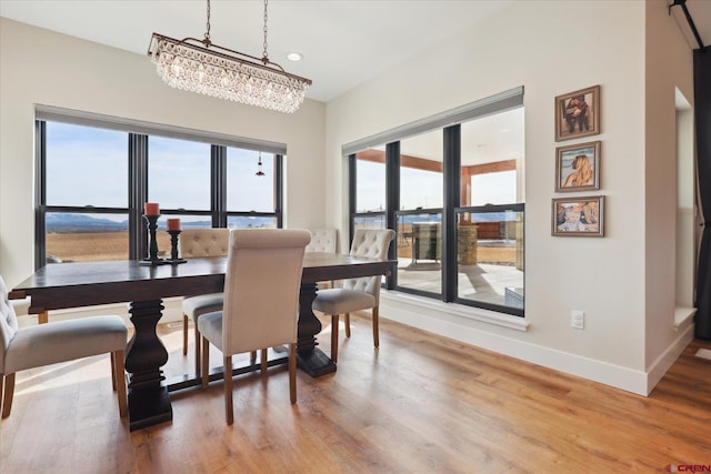 dining area with hardwood / wood-style flooring, plenty of natural light, and an inviting chandelier