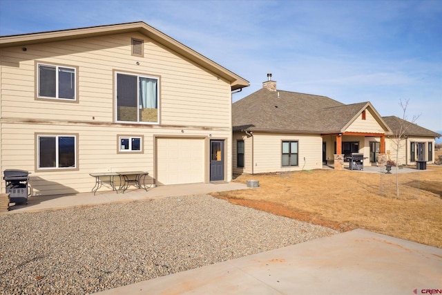 back of house featuring a garage and a patio area