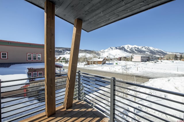 snow covered back of property featuring a mountain view