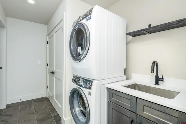 laundry area featuring cabinets, stacked washer / drying machine, and sink