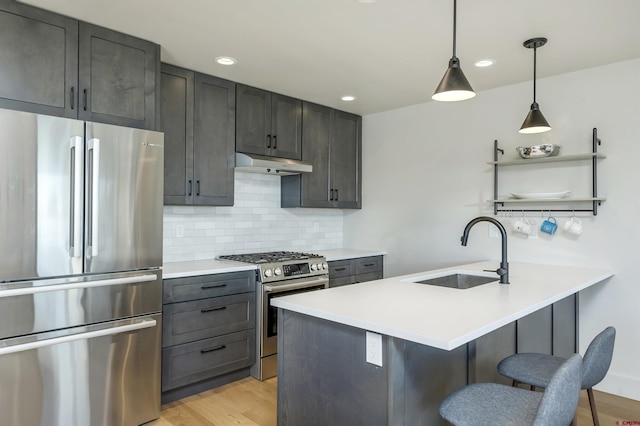 kitchen featuring tasteful backsplash, sink, a kitchen breakfast bar, hanging light fixtures, and stainless steel appliances