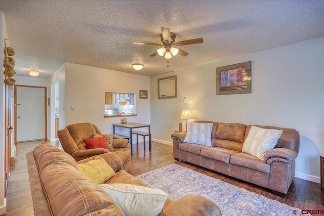 living room with hardwood / wood-style flooring, ceiling fan, and a textured ceiling