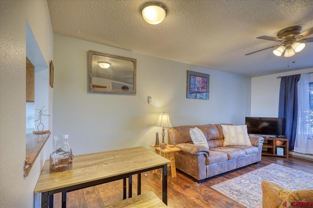 living room with ceiling fan, dark hardwood / wood-style flooring, and a textured ceiling