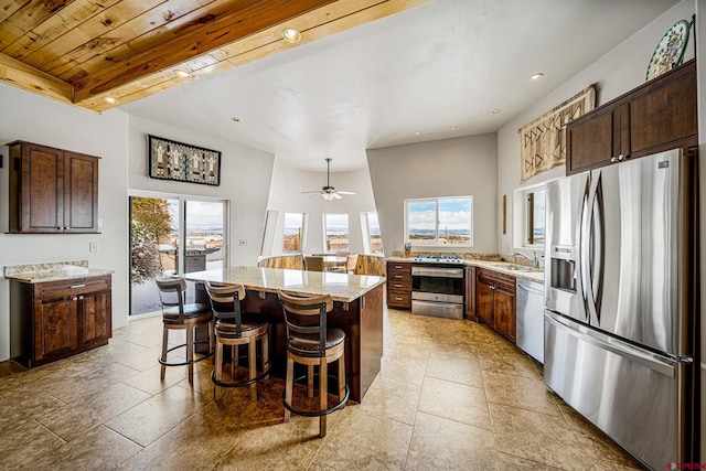 kitchen with a kitchen island, light stone countertops, appliances with stainless steel finishes, and plenty of natural light