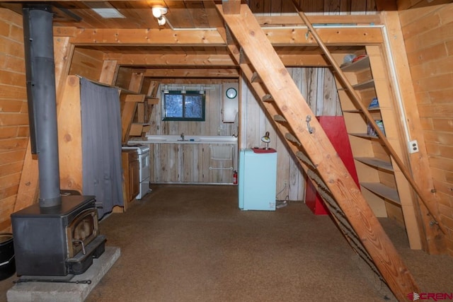 1015 E Stollsteimer Rd, Pagosa Springs, CO 81147 - basement featuring carpet floors, a wood stove, stairway, a sink, and wooden walls