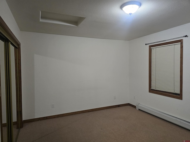 carpeted spare room featuring a baseboard heating unit