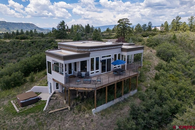 rear view of house featuring a deck with mountain view and a sunroom