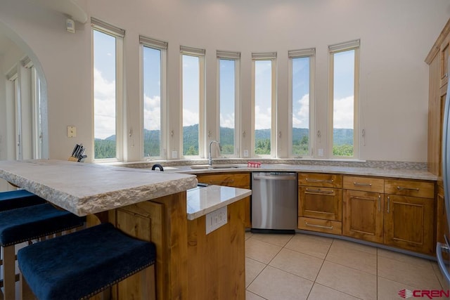 kitchen featuring a wealth of natural light, dishwasher, sink, a breakfast bar area, and light tile patterned floors