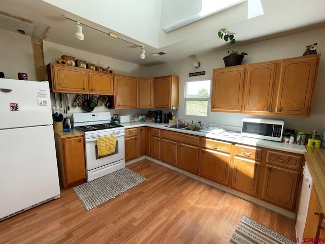 kitchen with sink, white appliances, light hardwood / wood-style flooring, and track lighting