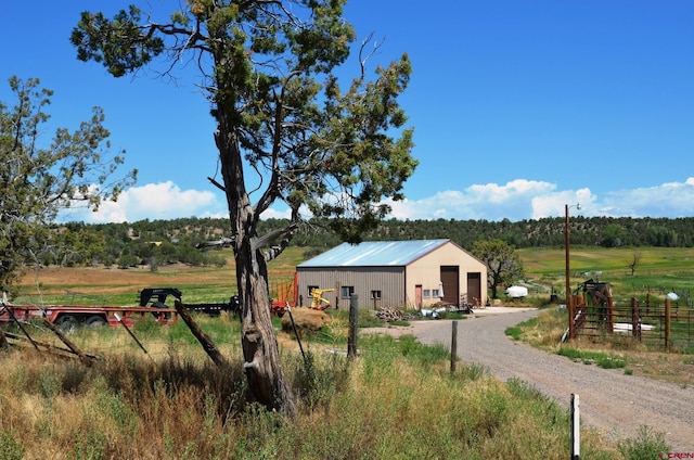 exterior space featuring a garage, an outbuilding, and a rural view