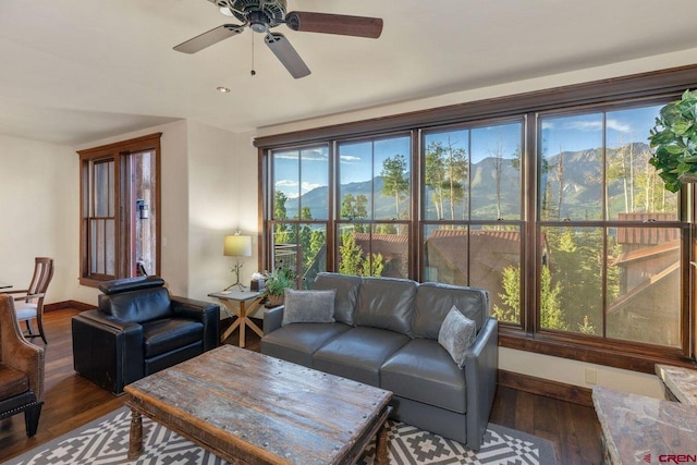 living room with dark wood-type flooring, ceiling fan, a healthy amount of sunlight, and a mountain view