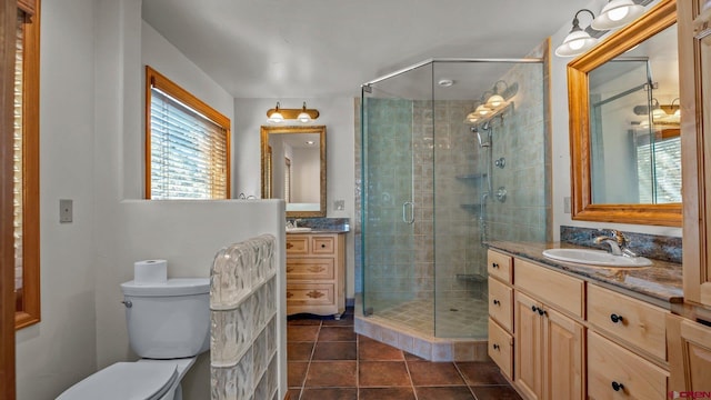 bathroom featuring tile patterned flooring, vanity, toilet, and a shower with shower door