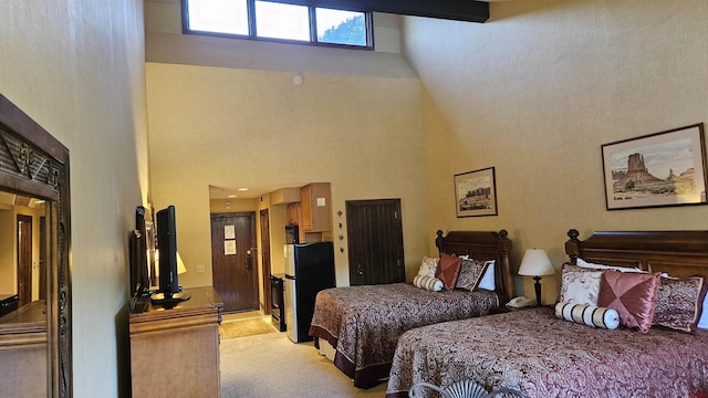 bedroom featuring stainless steel refrigerator, light carpet, and a high ceiling