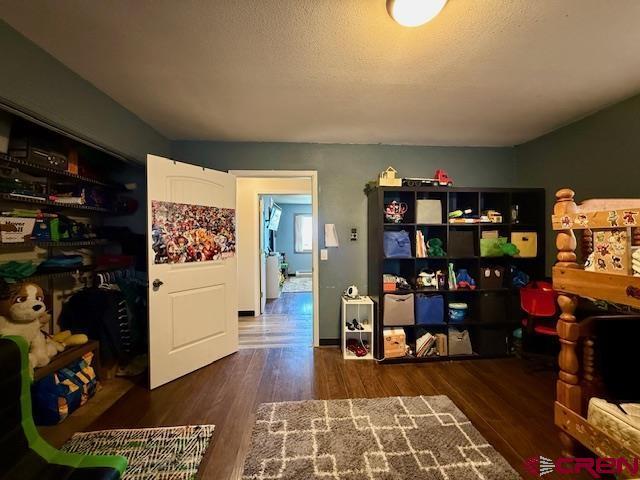 recreation room featuring dark hardwood / wood-style flooring and a textured ceiling