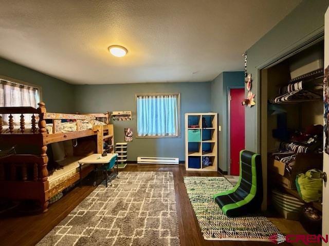 bedroom featuring a baseboard heating unit, hardwood / wood-style flooring, and a closet