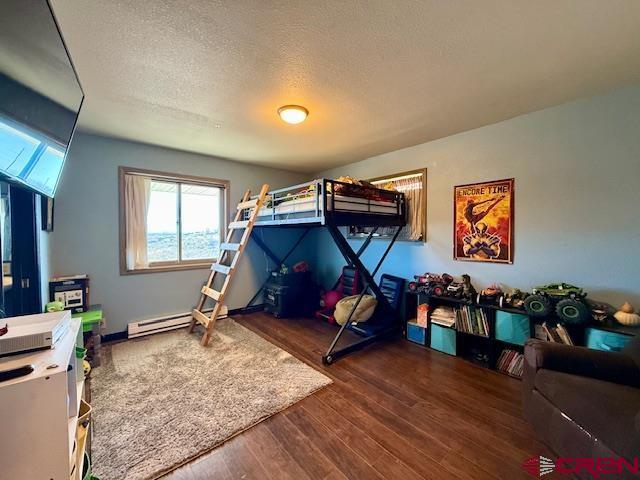 bedroom with dark hardwood / wood-style floors and a textured ceiling