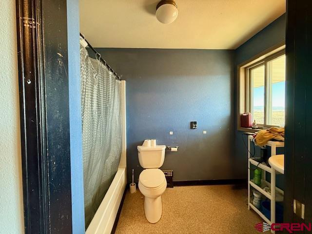 bathroom with shower / tub combo with curtain and toilet