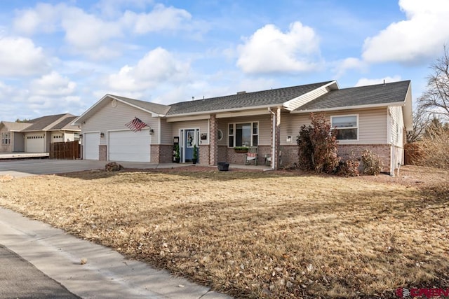 ranch-style home featuring a garage, covered porch, and a front lawn