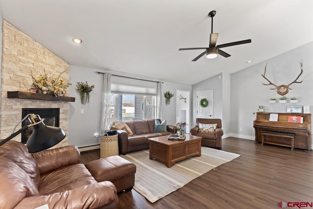 living room featuring a stone fireplace, vaulted ceiling, dark hardwood / wood-style floors, ceiling fan, and a baseboard heating unit