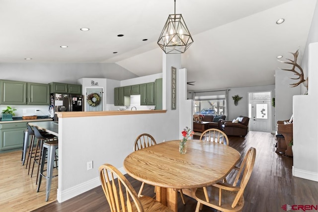 dining room featuring vaulted ceiling, wood-type flooring, and a chandelier