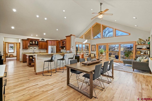 dining space featuring ceiling fan, high vaulted ceiling, and light hardwood / wood-style flooring