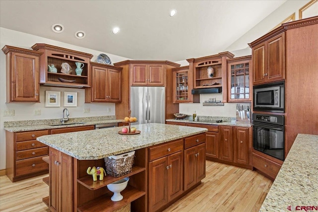 kitchen featuring sink, light stone counters, black appliances, a kitchen island, and light wood-type flooring