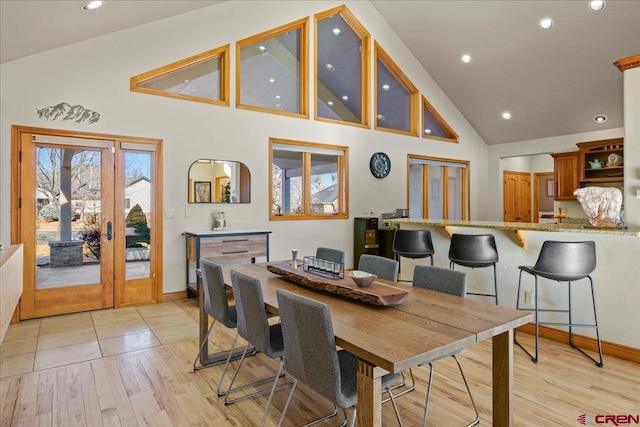 dining area with french doors, high vaulted ceiling, and light hardwood / wood-style flooring