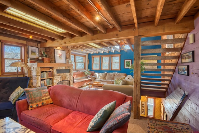 living room featuring beamed ceiling, a healthy amount of sunlight, and a stone fireplace