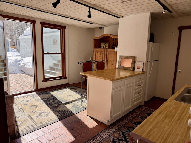 kitchen with white cabinetry, rail lighting, kitchen peninsula, and white fridge