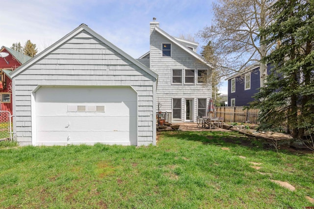 back of property with a garage, a yard, and an outbuilding