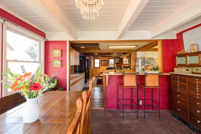 dining space featuring beamed ceiling and a chandelier